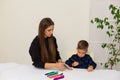 Little boy draws markers from lesson mother