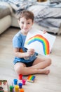 Little boy draws a rainbow on a sheet of paper in different colors