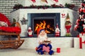 Little boy dressed like christmas elf sitting near the Christmas tree by the fireplace,eating cookies and drinking milk. Royalty Free Stock Photo
