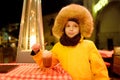 Little boy is drinking hot chocolate with whipped cream in street cafe or restaurant on european Christmas market. Tradition food Royalty Free Stock Photo