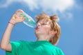 Little boy drinking water from a bottle against a blue sky Royalty Free Stock Photo