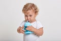 Little boy drinking water from bottle, wearing t shirt, looking directly at camera, posing against white background, male child Royalty Free Stock Photo