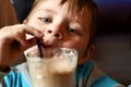 Little boy drinks a cocktail from a straw in a cafe Royalty Free Stock Photo