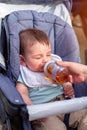Little boy drinks juice from a bottle while sitting in a baby carriage Royalty Free Stock Photo