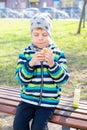 Little boy eating hamburger in the park. boy on the bench eating a hamburger. Snack on a walk
