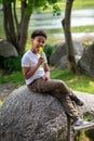 Little boy eating ice cream outdoors on hot summer day, sitting on rock, enjoying sweet dessert. Royalty Free Stock Photo