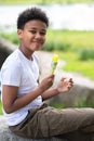 Little boy eating ice cream outdoors on hot summer day, sitting on rock, enjoying sweet dessert. Royalty Free Stock Photo