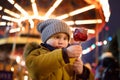 Little boy eating red apple covered in caramel on Christmas market. Traditional child& x27;s enjoyment and fun during Xmas time Royalty Free Stock Photo