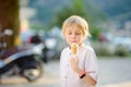 Little boy eating tasty ice cream cone outdoors during family stroll. Child have a snack to go. Gelato is loved delicacy of kids. Royalty Free Stock Photo