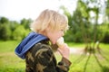 Little boy eating tasty ice cream outdoors during during family stroll. Child have a snack on the go. Gelato is loved delicacy of Royalty Free Stock Photo