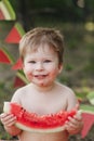 Little boy eating watermelon red in the garden sitting on the grass. Happy smiling face Royalty Free Stock Photo