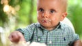 Little boy eats a cake with cream with his hands, dirtying his face