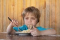 A little boy eats spaghetti with parmesan cheese. He is dreamy