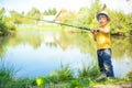 Little boy is engaged in fishing in a pond. Child with a dairy i Royalty Free Stock Photo