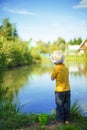 Little boy is engaged in fishing in a pond. Child with a dairy i Royalty Free Stock Photo