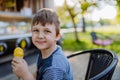 Little boy enjoying ice cream in park during hot summer day, looking at camera and smiling. Royalty Free Stock Photo