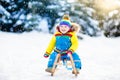 Little boy enjoying a sleigh ride. Child sledding. Toddler kid riding a sledge. Children play outdoors in snow. Kids sled in the Royalty Free Stock Photo