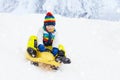 Little boy enjoying a sleigh ride. Child sledding. Toddler kid riding a sledge. Children play outdoors in snow. Kids sled in the