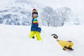 Little boy enjoying a sleigh ride. Child sledding. Toddler kid riding a sledge. Children play outdoors in snow. Kids sled in the Royalty Free Stock Photo