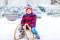 Little boy enjoying sleigh ride during snowfall. Child sledding on snow. Preschool kid riding a sledge. Child play Royalty Free Stock Photo