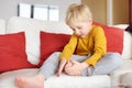 Little boy examines the sore leg sitting on the couch indoors. Trauma, bruise, splinter