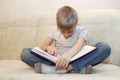 little boy fell asleep sitting at home on beige sofa reading book. concept of hard educational process Royalty Free Stock Photo