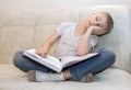 little boy fell asleep sitting at home on beige sofa reading book. concept of hard educational process Royalty Free Stock Photo