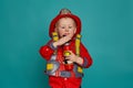 A little boy in a fireman costume plays and dreams of putting out the fire. Fireman on a blue background. Royalty Free Stock Photo