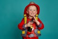 A little boy in a fireman costume plays and dreams of putting out the fire. Fireman on a blue background. Royalty Free Stock Photo