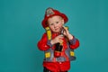 A little boy in a fireman costume plays and dreams of putting out the fire. Fireman on a blue background. Royalty Free Stock Photo