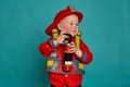 A little boy in a fireman costume plays and dreams of putting out the fire. Fireman on a blue background. Royalty Free Stock Photo