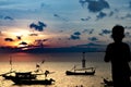 Little boy fishes on a pier in a rustic port. Silhouette of a boy at sunset, holding a fishing pole and looking at the setting sun Royalty Free Stock Photo