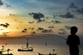 Little boy fishes on a pier in a rustic port. Silhouette of a boy at sunset, holding a fishing pole and looking at the setting sun Royalty Free Stock Photo