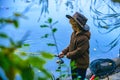 Little boy fishing in overalls from a dock on lake or pond. Child with a fishing rod standing by the water. Young Royalty Free Stock Photo