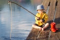 A little boy fishing and wants to catch the biggest fish. Picturesque scene of cute little boy fishing from wooden dock Royalty Free Stock Photo