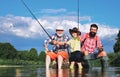 Little boy fly fishing on a lake with his father and grandfather. Summer day. Happy grandfather, father and grandson Royalty Free Stock Photo