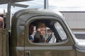 a little boy in the form of a Soviet soldier in the cockpit of an army car participates in a parade in honor of victory day