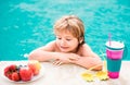 Little boy with fresh cocktail and fruits on watter pool in the summer day. Kid in swimming pool relax and swim in blue