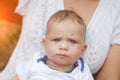 A little boy with a funny face sitting at his mom knees. He has beautiful blue eyes Royalty Free Stock Photo