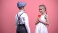 Little boy gifting red heart-shaped lollipop to girlfriend, sweet romantic gift Royalty Free Stock Photo