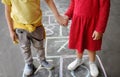 Little boy and girl on background hopscotch which drawn on asphalt. Children playing hop scotch game on playground outdoors on a Royalty Free Stock Photo