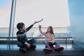 Little boy and girl, brother and sister playing with toy airplanes sitting on the floor by the panoramic windows of the airport Royalty Free Stock Photo