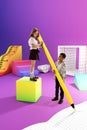 Little boy and girl, children playing with 3D models of school supplies over purple background Royalty Free Stock Photo