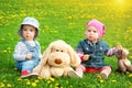 Little boy and girl in hats sitting on the field with soft toys in summer Royalty Free Stock Photo
