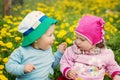 Little boy and girl in hats sitting on the field with soft toys in summer Royalty Free Stock Photo