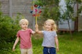 Little boy and girl having fun during walk. Happy child with pinwheel