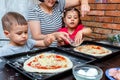Little boy and girl helping mom make pizza at home Royalty Free Stock Photo