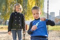 Little boy and girl playing in autumn park, children sitting on swing blow soap bubbles Royalty Free Stock Photo