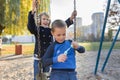 Little boy and girl playing in autumn park, children sitting on swing blow soap bubbles Royalty Free Stock Photo