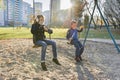 Little boy and girl playing in autumn park, children sitting on swing blow soap bubbles Royalty Free Stock Photo